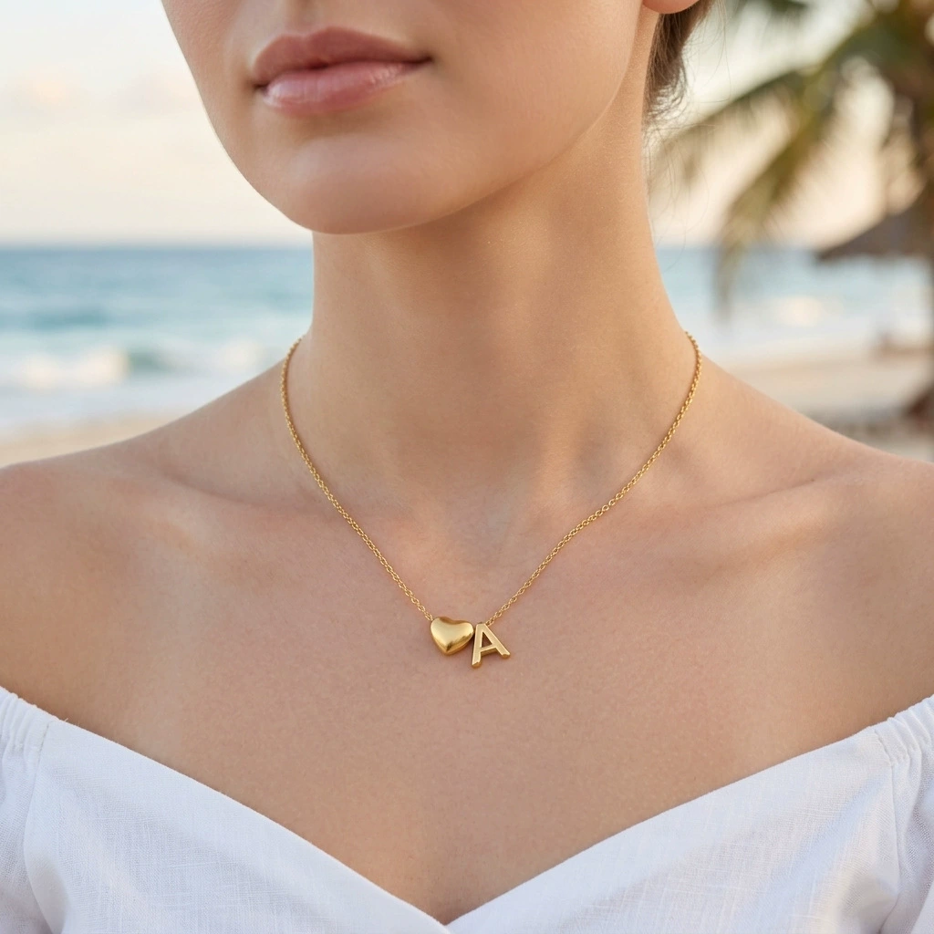 Model wearing a gold-tone necklace with a heart charm and the letter A